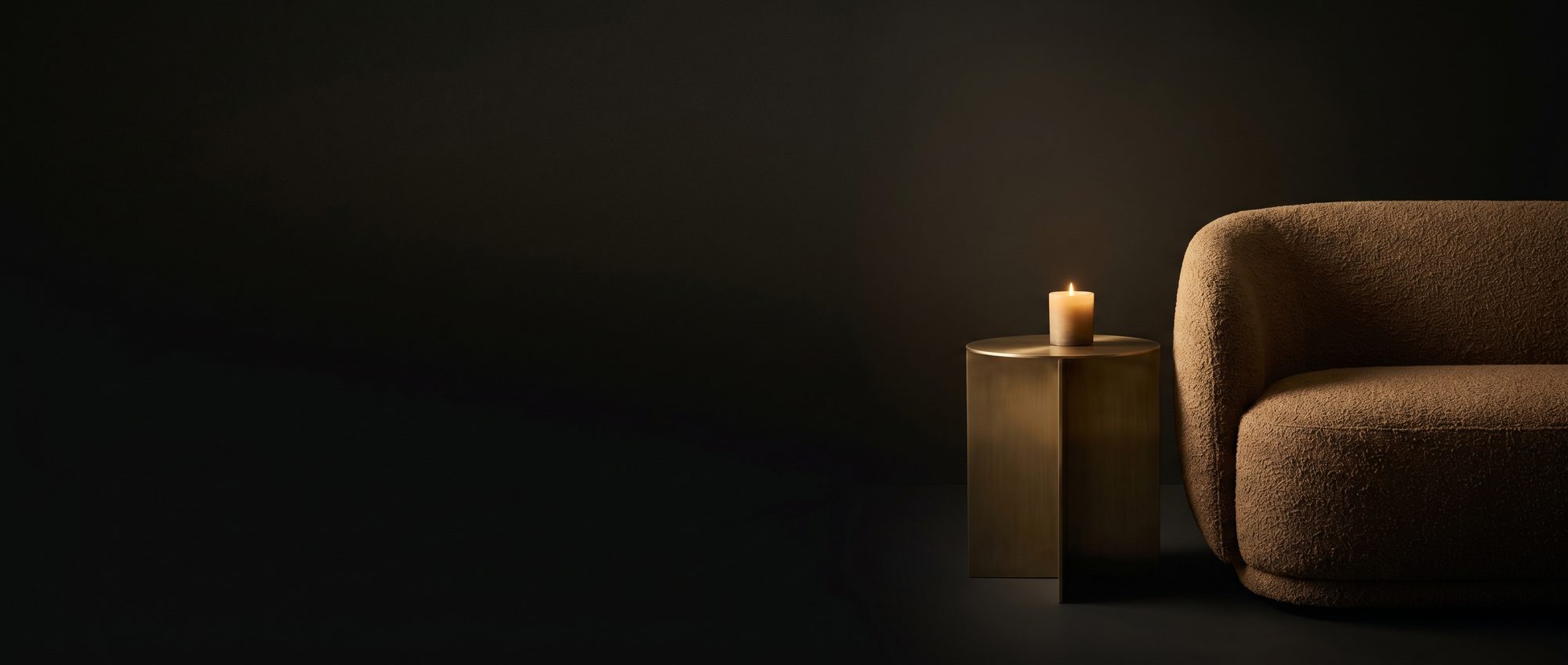 A bronze sofa arm and brass side table lit by candlelight